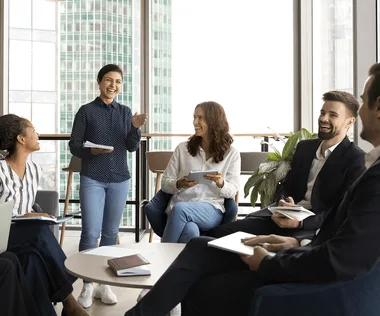A diverse group of professionals, seated in a modern office setting, engaged in a lively and casual discussion.