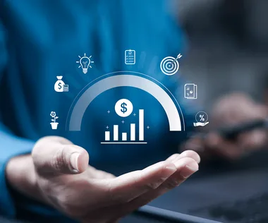 Hand holding holographic financial icons, including bar graph, dollar sign, and light bulb, symbolizing business growth and strategy.