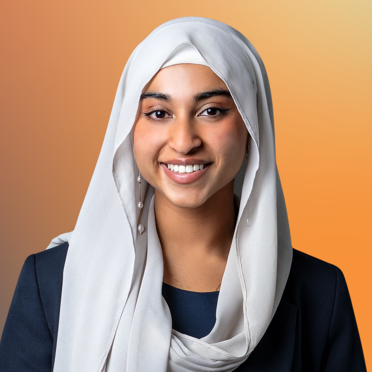 A smiling woman wearing a light beige hijab and dark blazer against a gradient orange background.