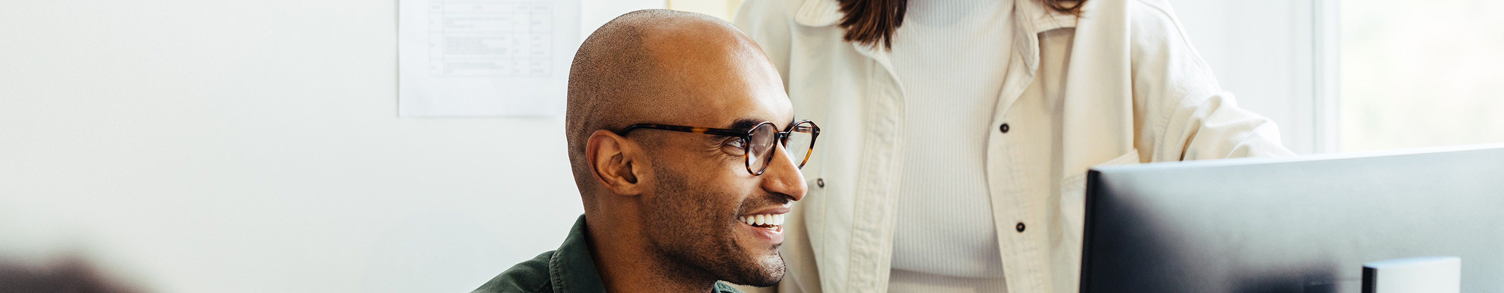 man and woman smile in front of computer while working