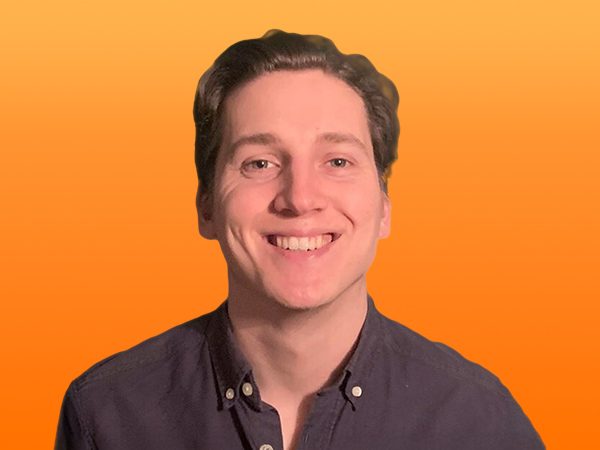 Smiling person with short hair wearing a dark shirt, set against an orange background.