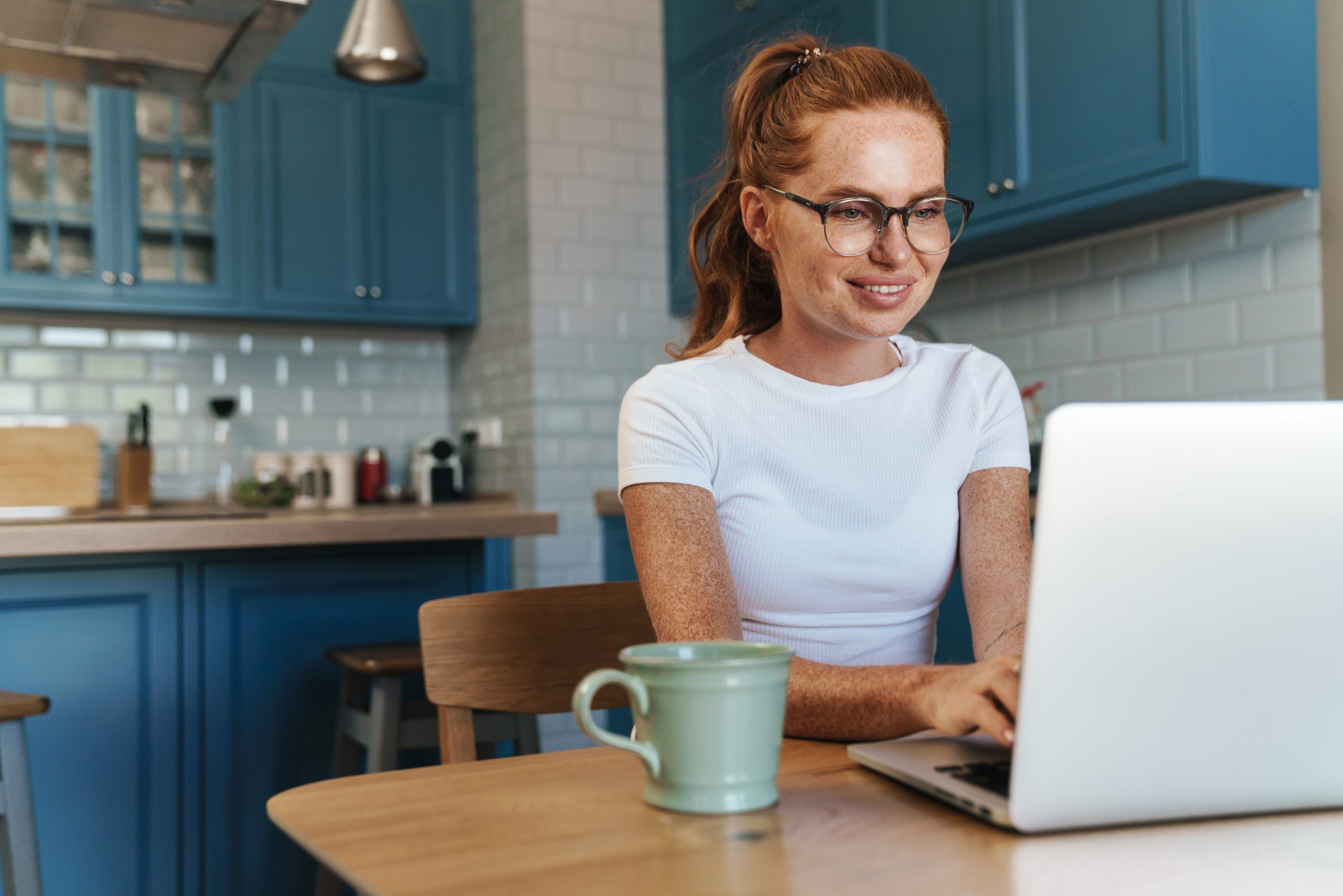 Lady in kitchen at home working on laptop