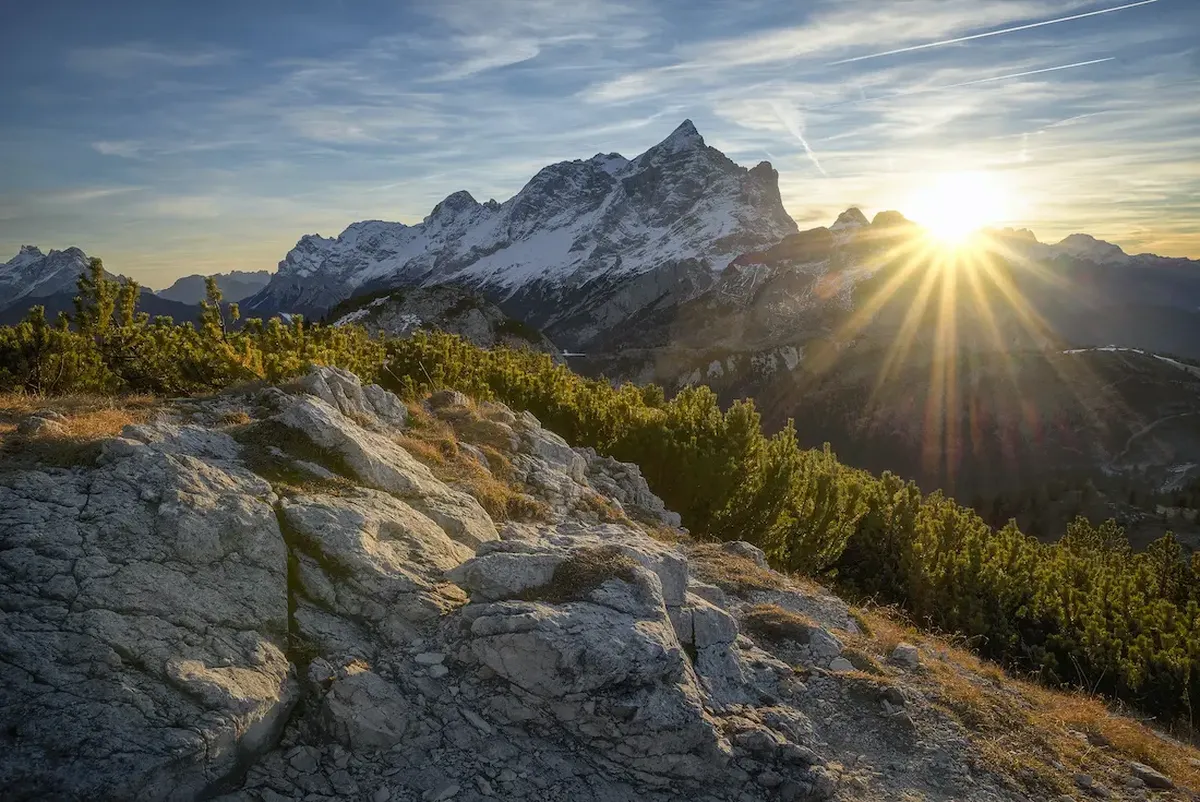 Sun rays behind snow covered mountains