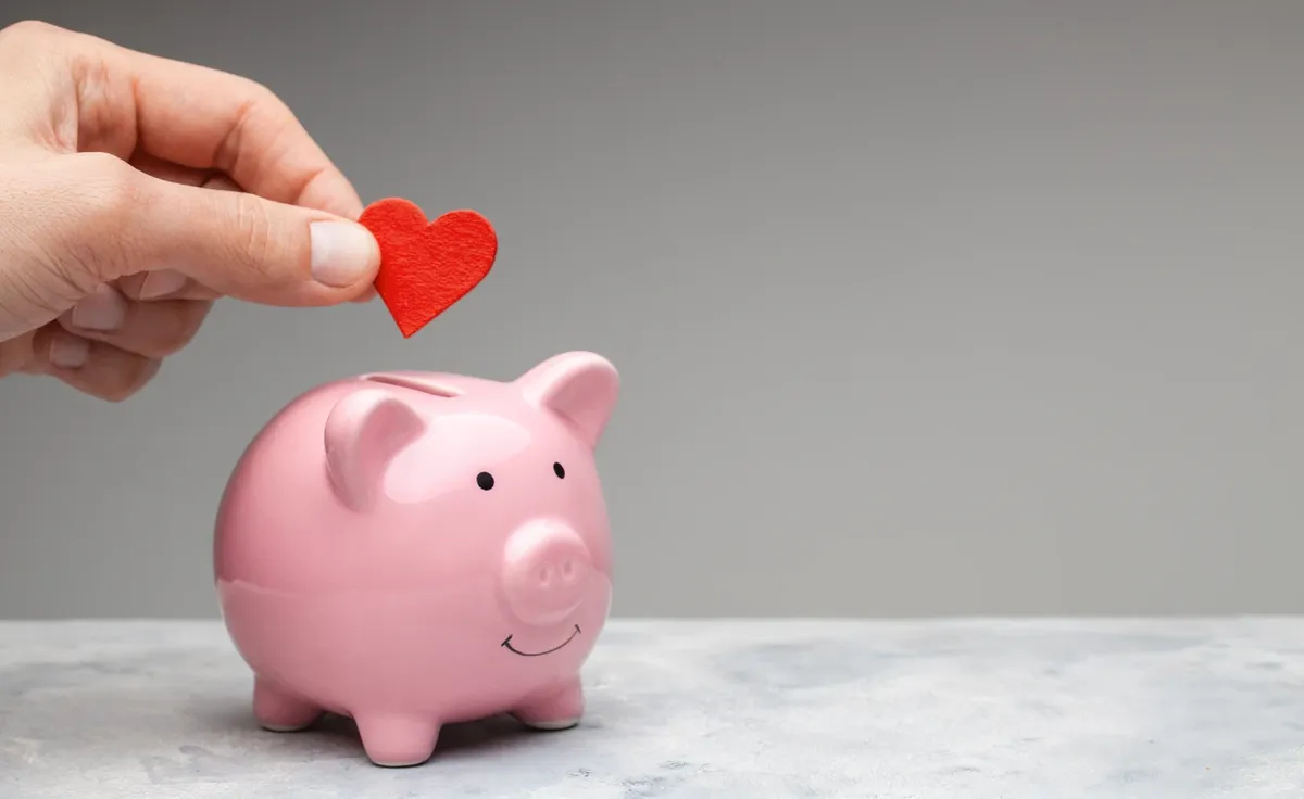 donor-man-holds-red-heart-his-hand-goes-piggy-bank-as-donation