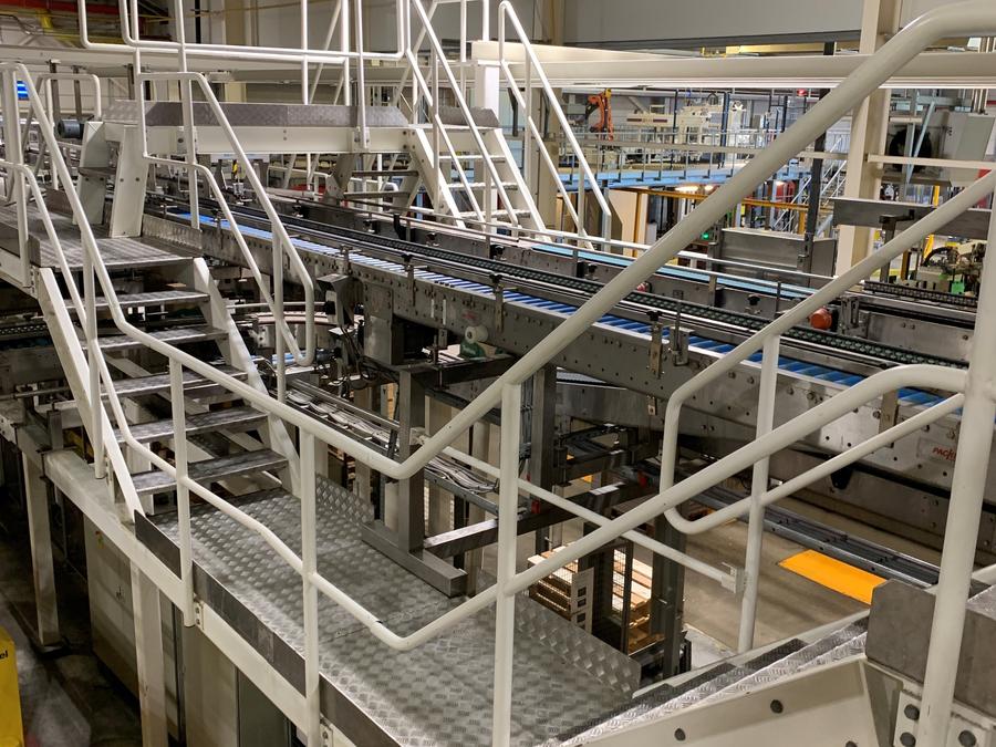 Witte trappen en bordessen boven een productielijn in een fabriek