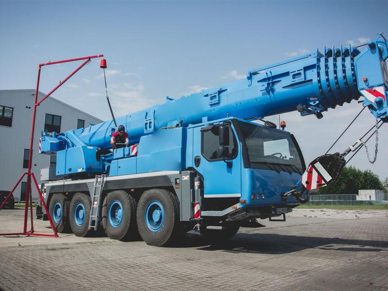 Rode mobiele arm met een ankerpunt naast een blauwe kraanwagen