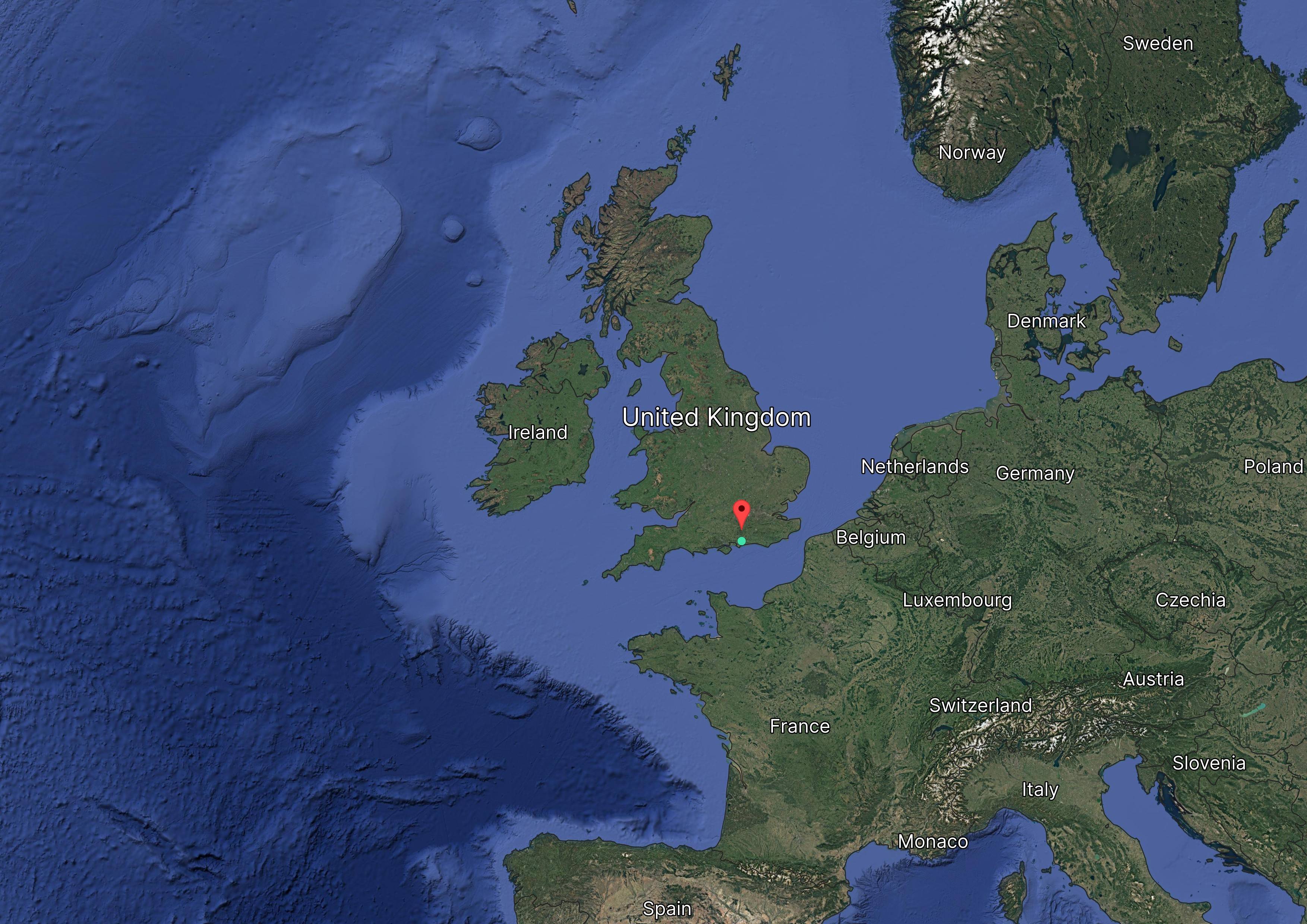 Satellite map showing the United Kingdom and surrounding countries in Europe, with a red marker on southern England.
