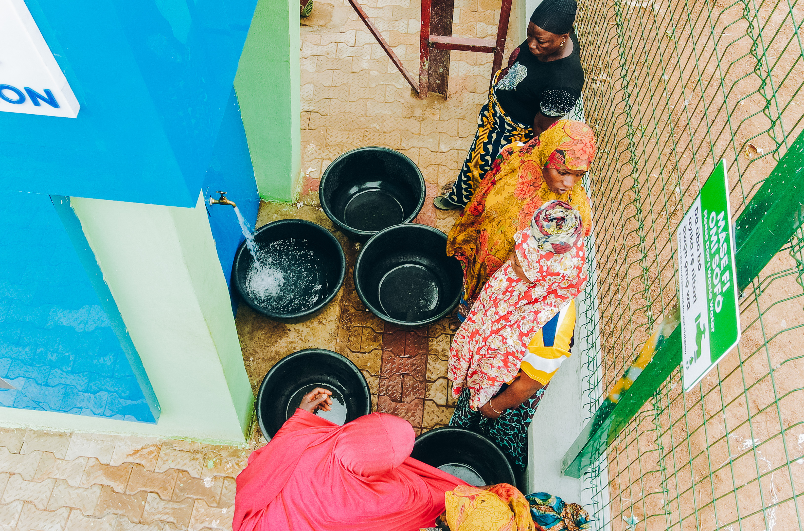 Reliable water service changes daily life. At a Fairaction water kiosk, women collect water from a system designed to keep working beyond construction, because lasting access, not one off installation, is what supports poverty reduction.