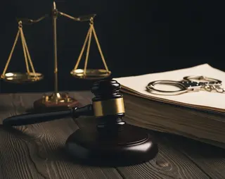 Weegschaal, hamer gerechtshof, handboeien en documenten liggen op tafel