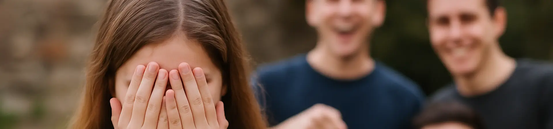 Meisje houdt handen voor haar gezicht, omdat jongens om haar lachen.