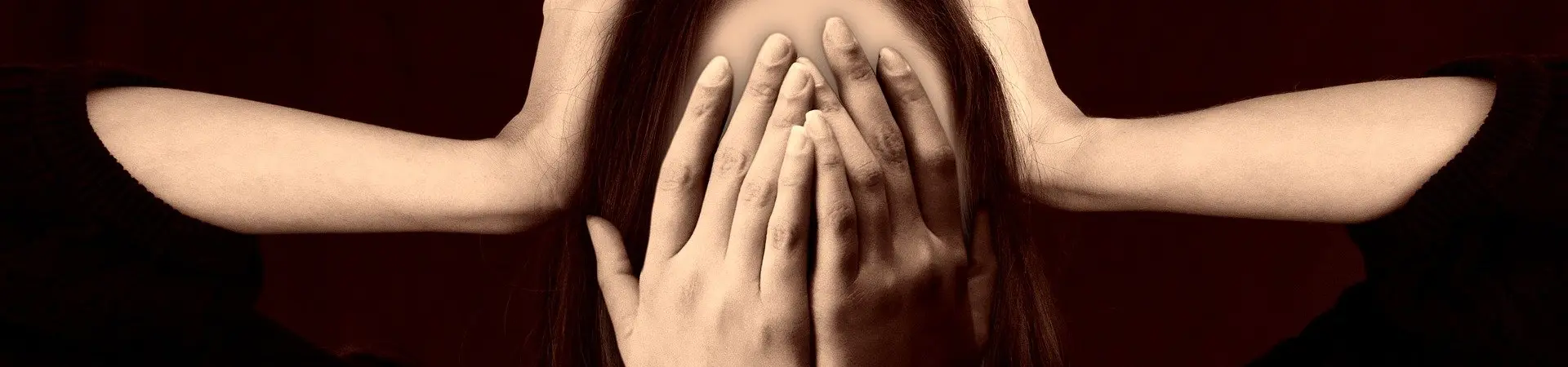 Een vrouw houdt haar handen voor haar ogen en op haar hoofd. 