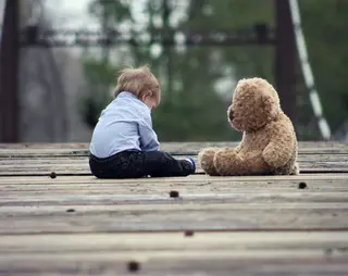 Kind zit met grote knuffelbeer op een vlonder