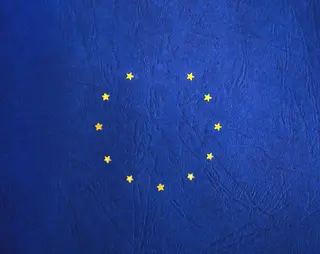 11 gele sterren in een cirkel op een blauwe achtergrond