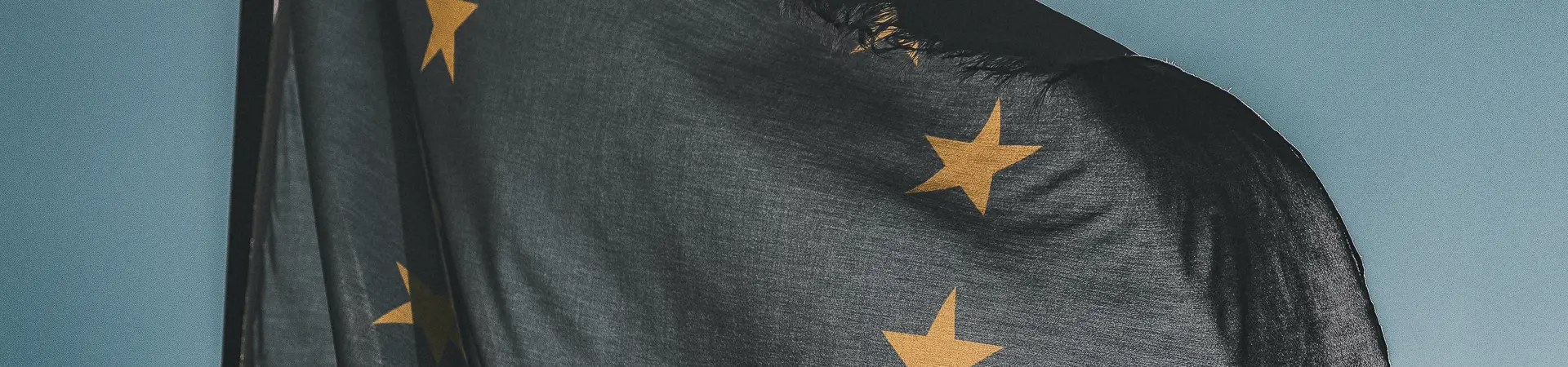 Europese Unie vlag hangt wapperend buiten op een bewolkte dag met zon. 