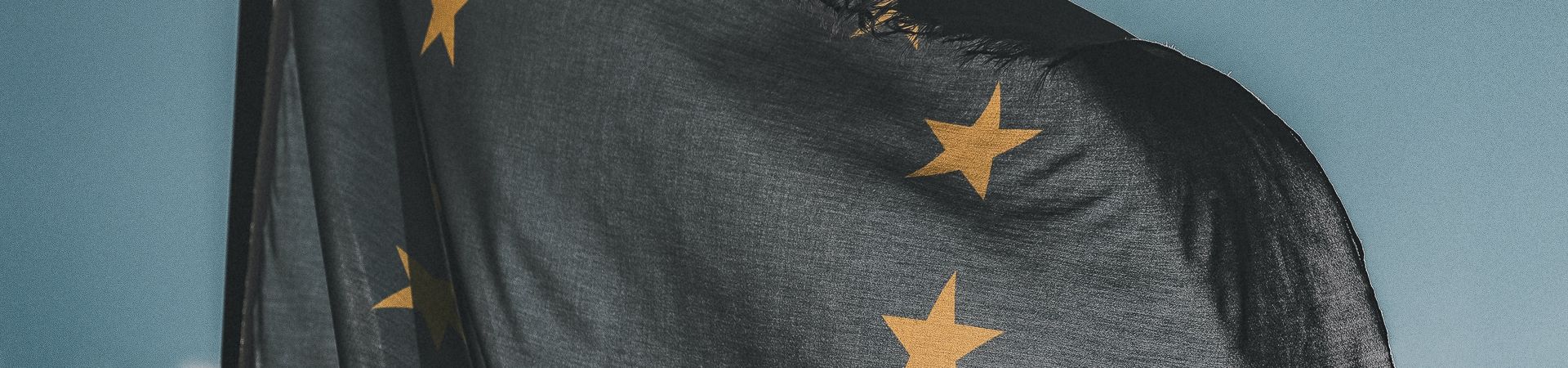 Europese Unie vlag hangt wapperend buiten op een bewolkte dag met zon.