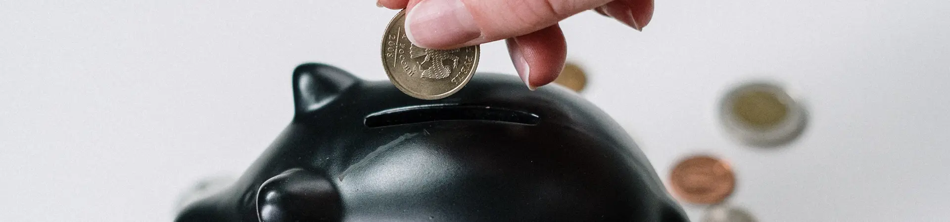 Vrouw stopt geld in een zwart spaarvarken.