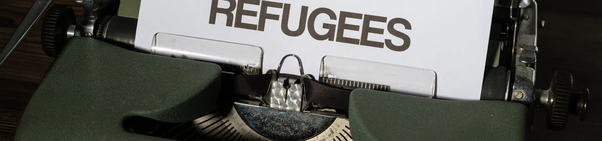 Typemachine met een blad erin met de tekst refugees