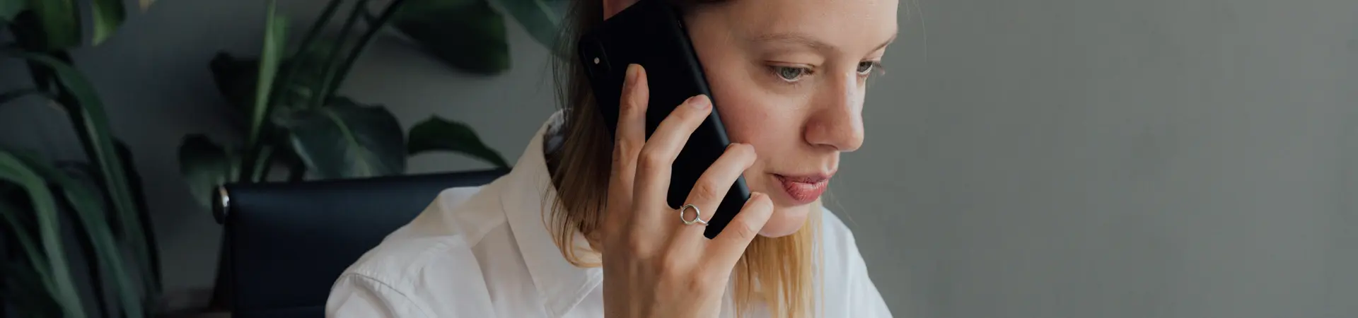 Werkgever aan wit bureau die een medewerker met oproepovereenkomst oproept via de telefoon om te komen te werken.