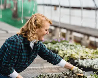 Mevrouw die werkt in een kas met plantjes en bloemen