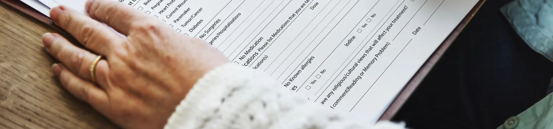 Letselschadeformulier wordt door een vrouw aan een houten bureau ingevuld met een rode pen. 