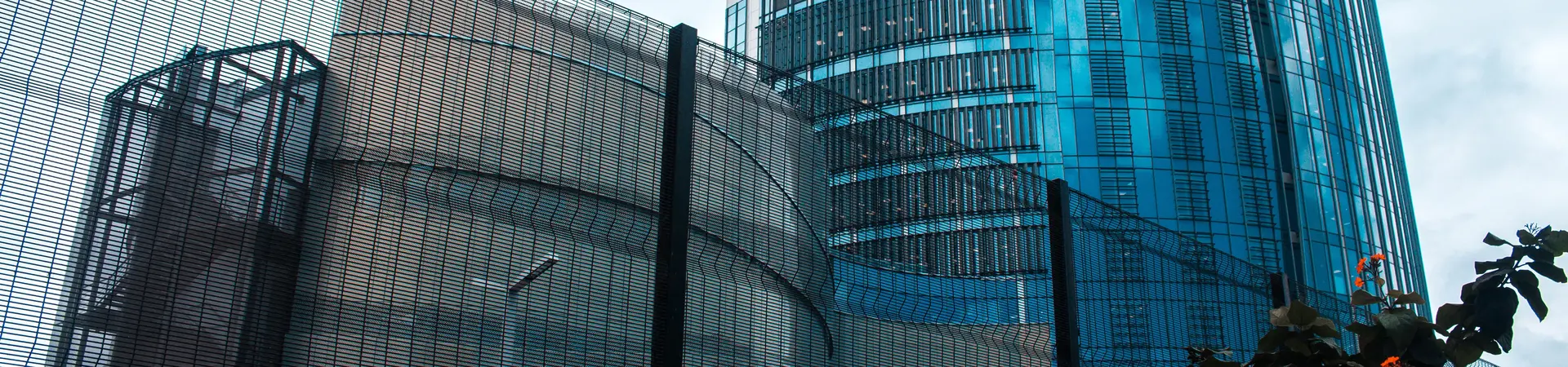 Een groot gebouw met het hoofdkantoor van een bank met daarvoor een parkeerplaats voor werknemers. 