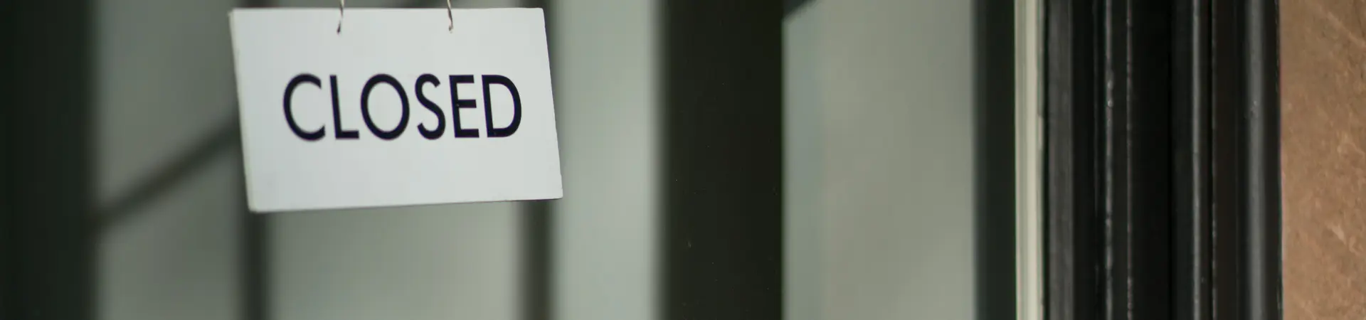 winkel gesloten door faillissement raampartij hangt wit bordje aan kozijn met zwarte tekst erop geschreven closed.