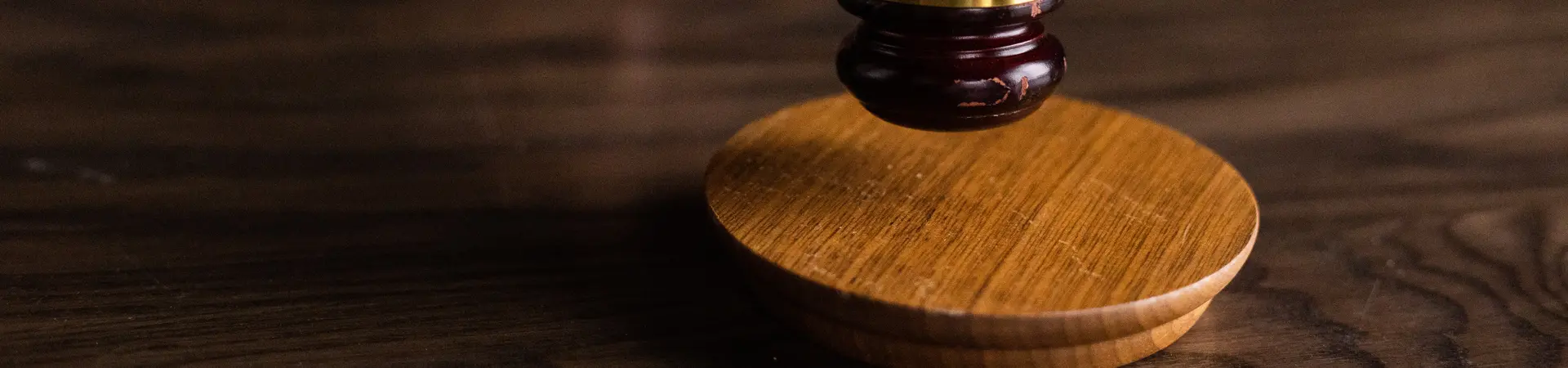 Man slaat met rechters hamer op een bruin houten bureau. 