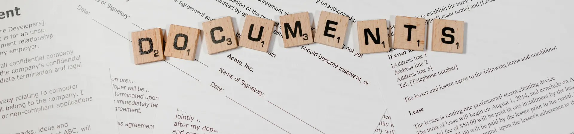 Diverse documenten liggen naast elkaar. Er liggen houten letters op de documenten die het woord documents weergeven. 