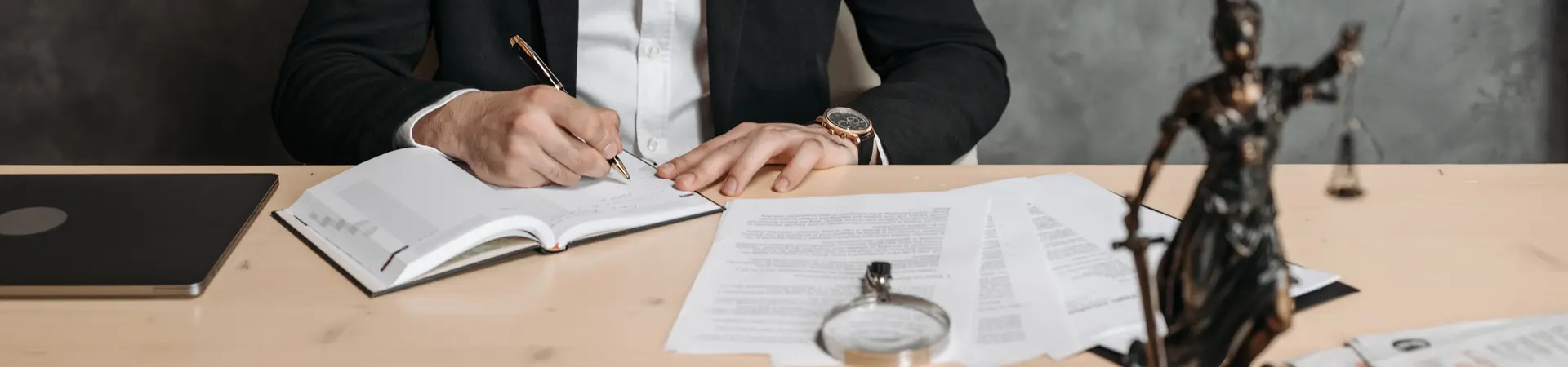 Man in pak zit achter zijn bureau en schrijft in een agenda