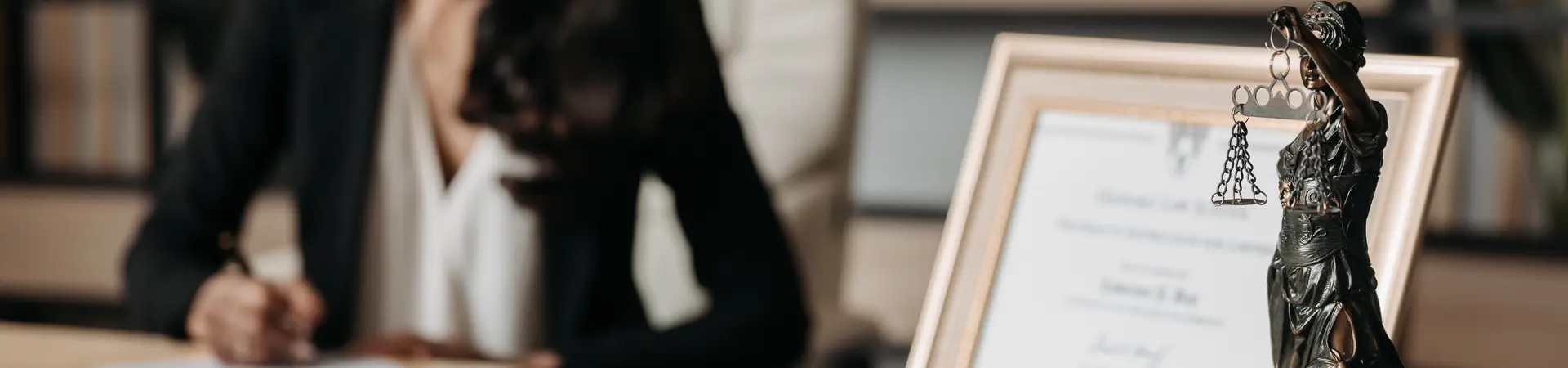 Actuele rechtspraken arbeidsrecht wordt dor vrouw aan houten bureau doorgelezen met een pen gemarkeerd. 