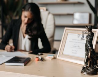 Actuele rechtspraken arbeidsrecht wordt dor vrouw aan houten bureau doorgelezen met een pen gemarkeerd.