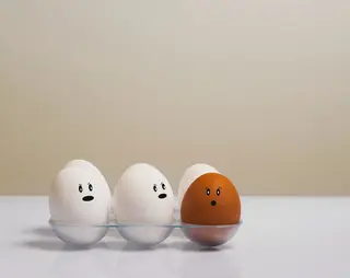 Twee eieren met gezichtjes kijken geschrokken naar een ander ei.