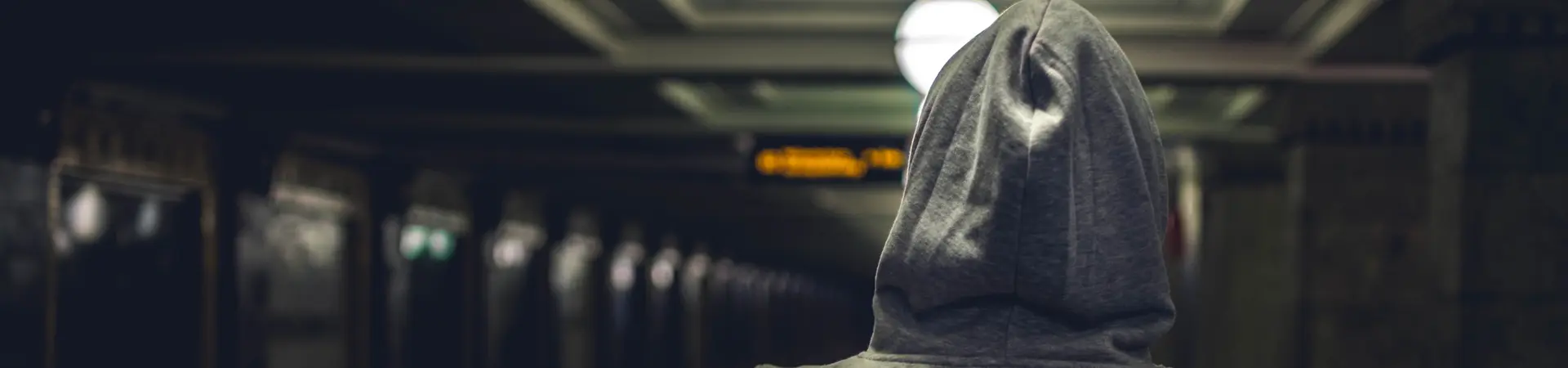 Jongere met hoodie loopt op een treinstation.