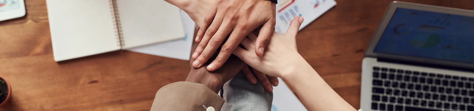 Groep werknemers slaan hand bovenop elkaar. 