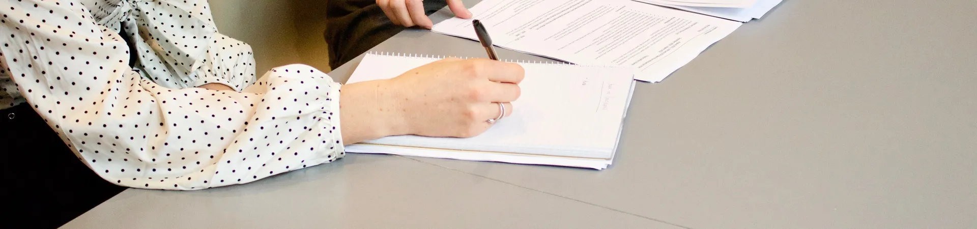 Arbeidsovereenkomst wordt door twee vrouwen aan tafel ondertekend met een pen. 