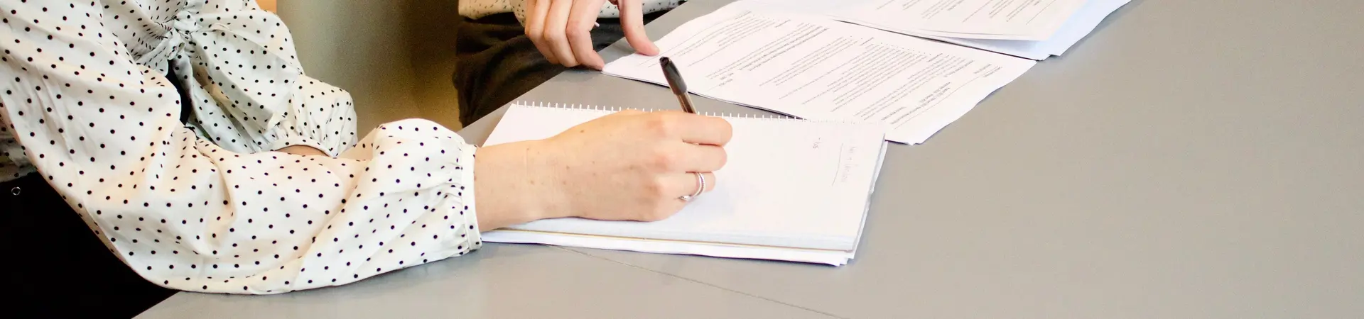 Arbeidsovereenkomst wordt door twee vrouwen aan tafel ondertekend met een pen