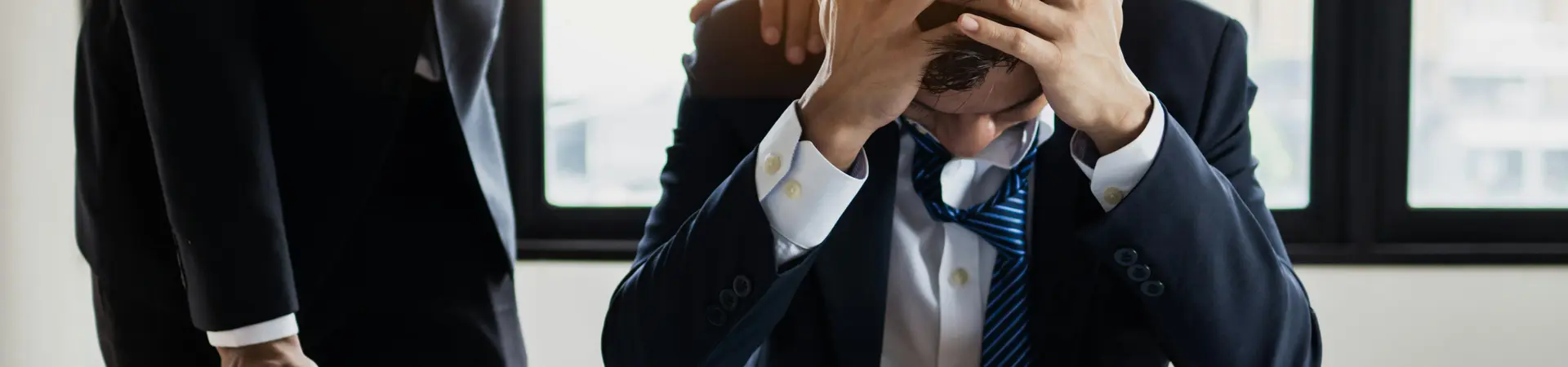 Man in pak zit achter bureau met zijn handen in het haar