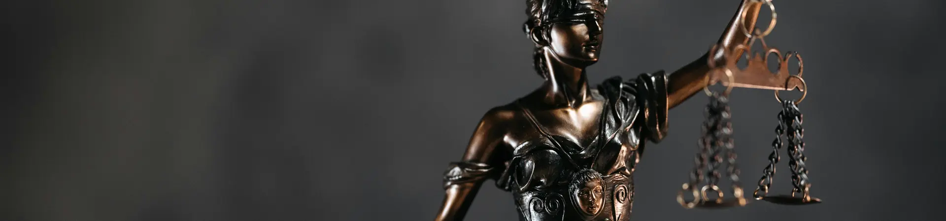 Bronzen beeld van Vrouwe Justitia op een donkere achtergrond