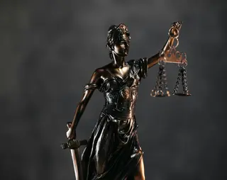 Bronzen beeld van Vrouwe Justitia op een donkere achtergrond