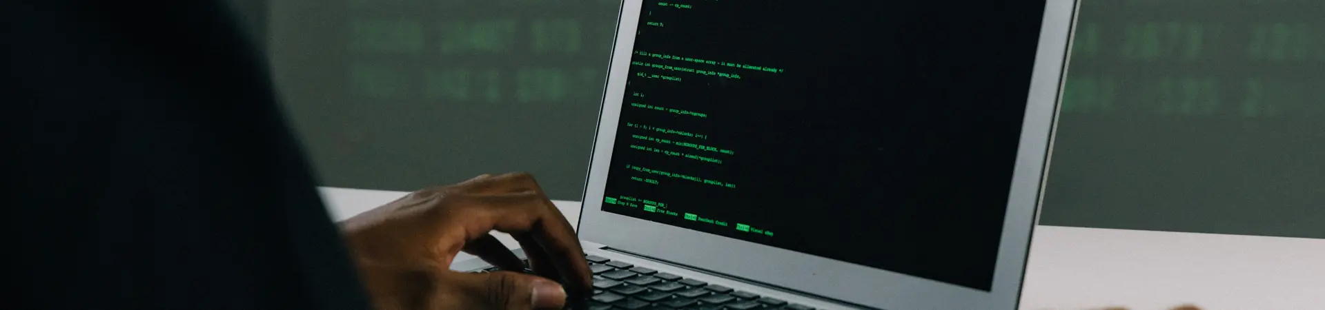 iemand met zwarte trui zit achter een laptop met zwart scherm en groene letters