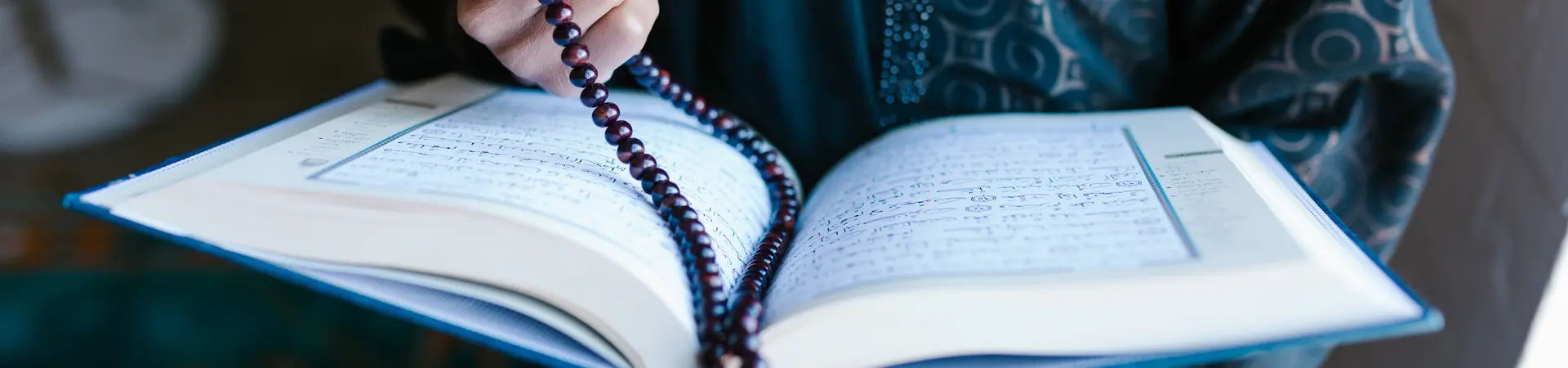 Vrouw in lang gewaad met koran en ketting in haar hand