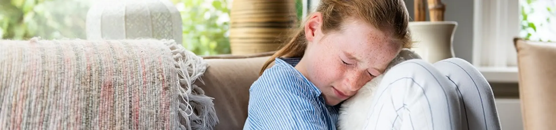 meisje zit met opgetrokken en geknepen ogen op een bank.
