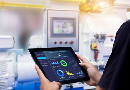 Intelligentes Industrie-Steuerungskonzept. Hände halten Tablette auf unscharfen Automatisierungsmaschine als Hintergrund.