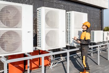 Arbeiter bei der Wartung von Klimaanlagen oder Wärmepumpen mit digitalem Tablet
