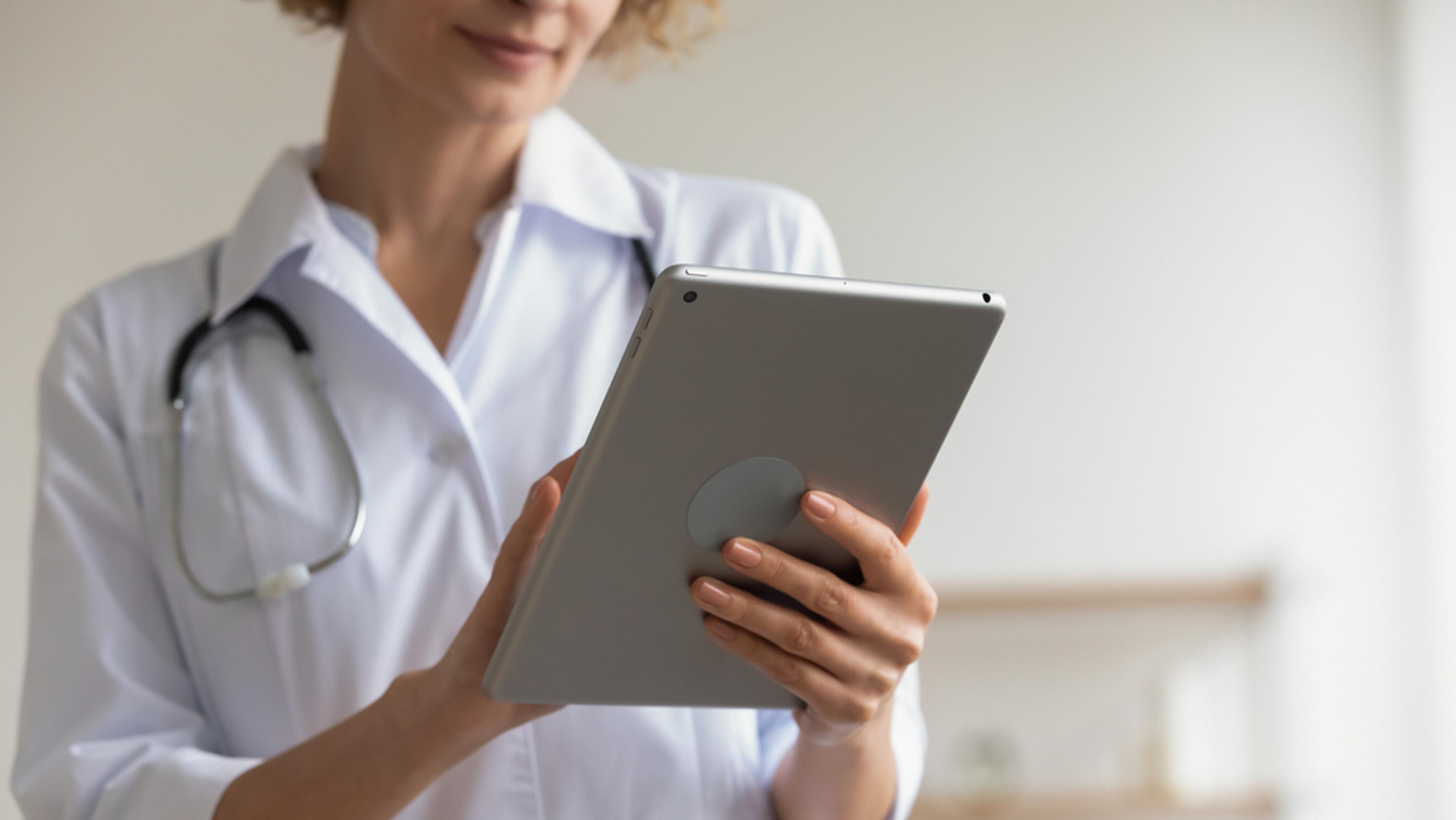 Female professional medic doctor holding modern pad using digital tablet remote telemedicine app in .jpg