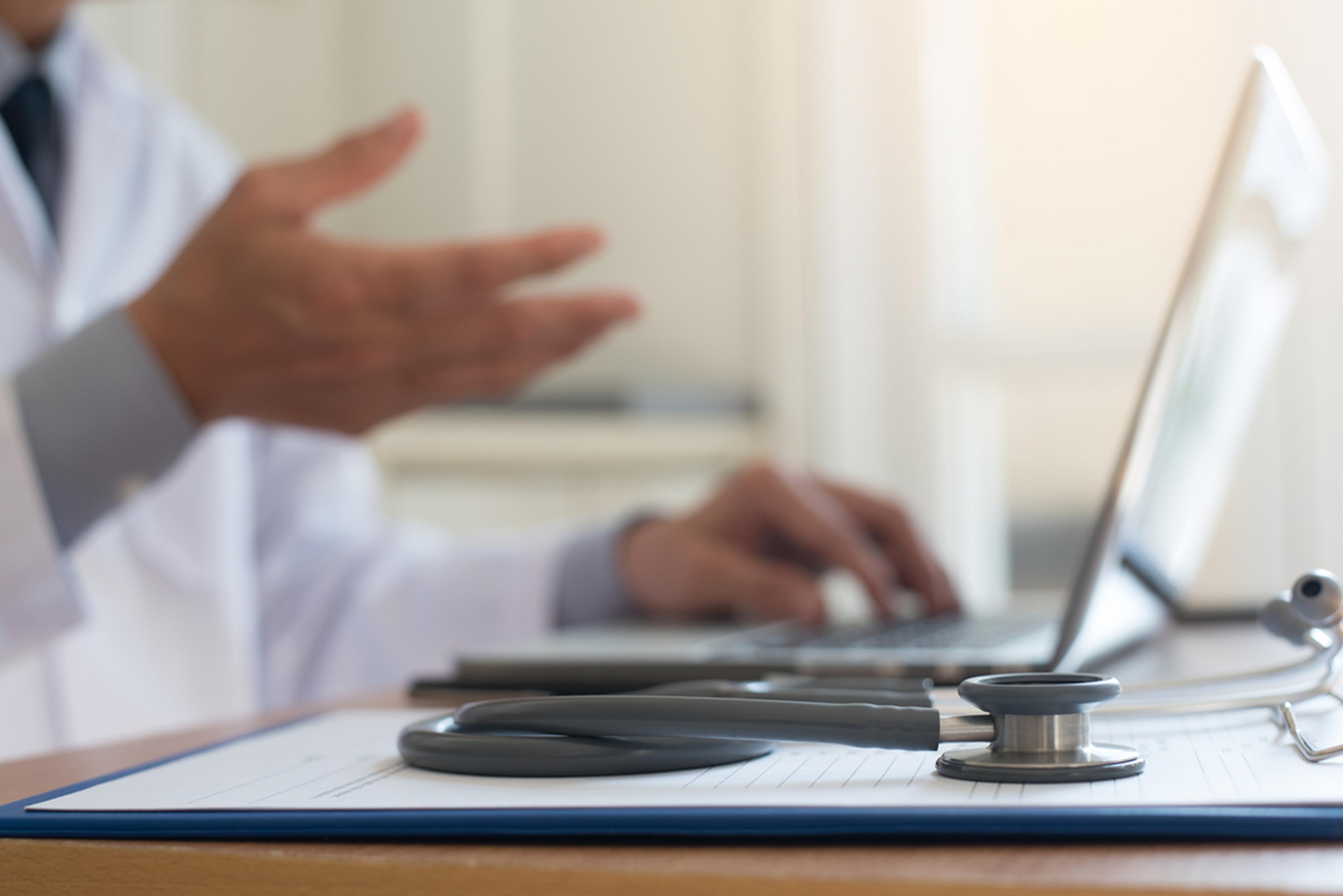 Doctor on video conference progress via laptop computer and stethoscope on clipboard