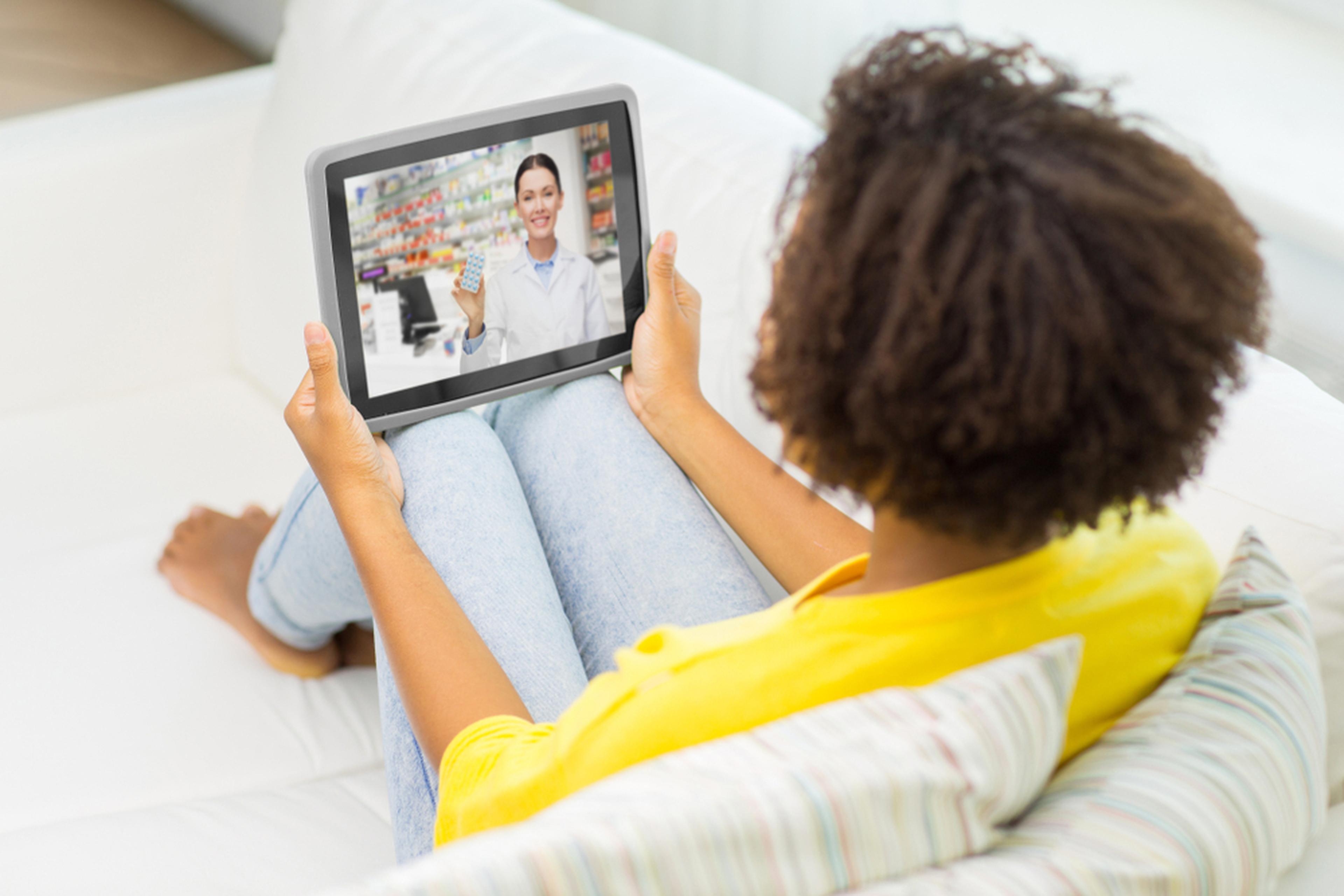 Young Woman sitting on a sofa doing a telehealth video with her doctor