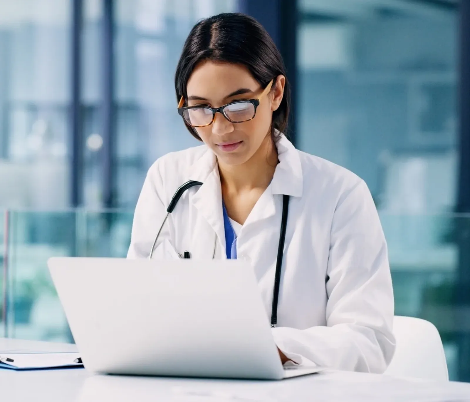 A doctor reviewing a telehealth visit on a laptop