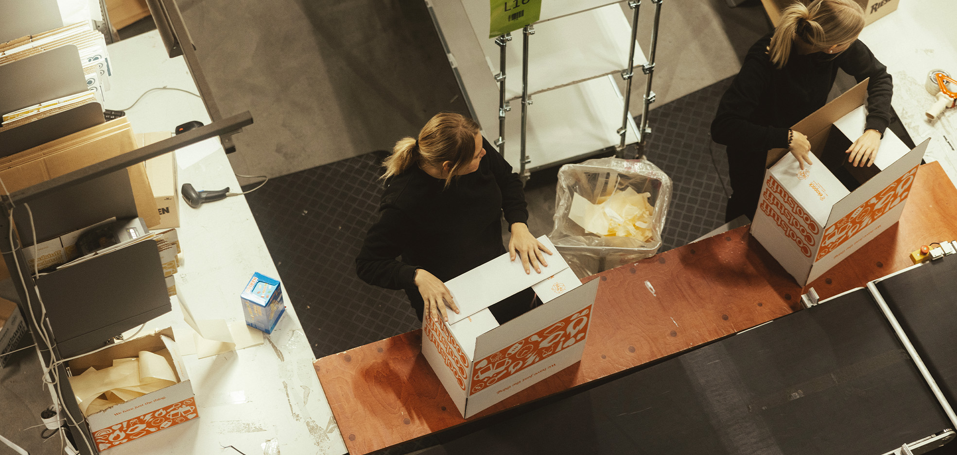 Två kvinnor står och packar lådor på ett lager