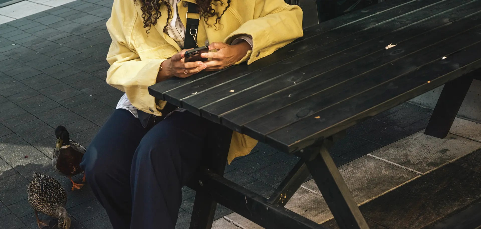 Kvinna sitter på en bänk och kollar i sin telefon